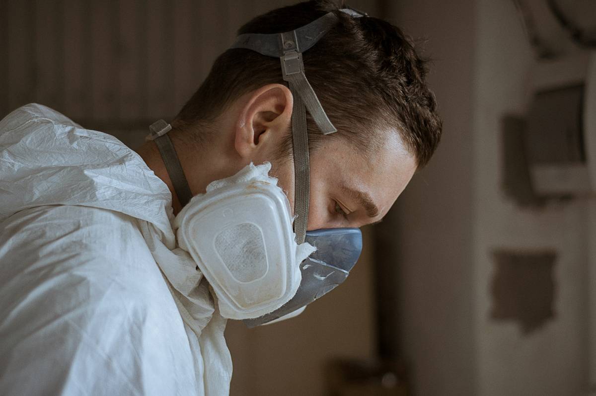 A worker in protective gear removing asbestos safely
